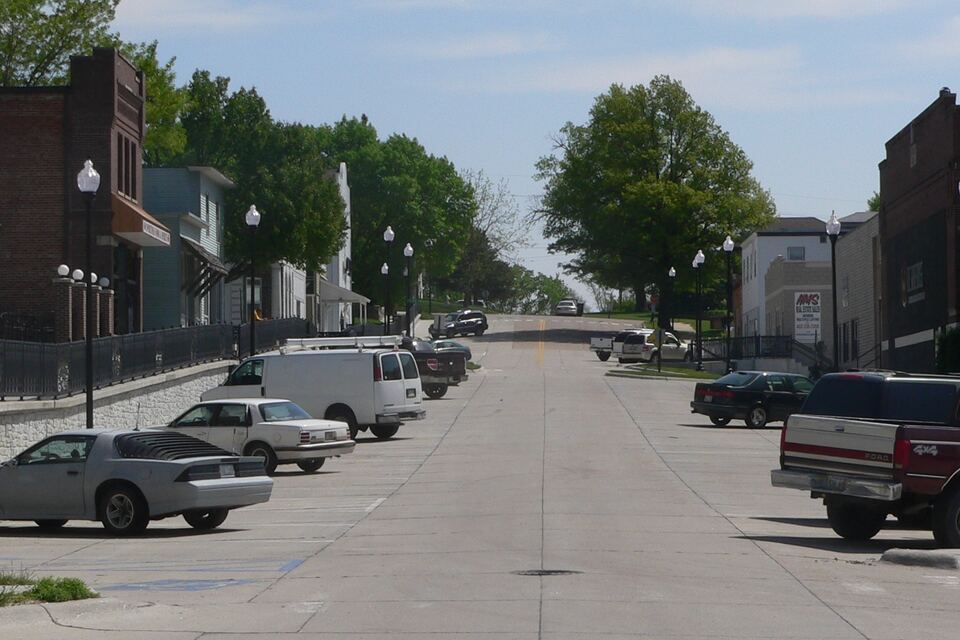 Small-town main street with brick storefronts, street lamps and parked cars and trucks.