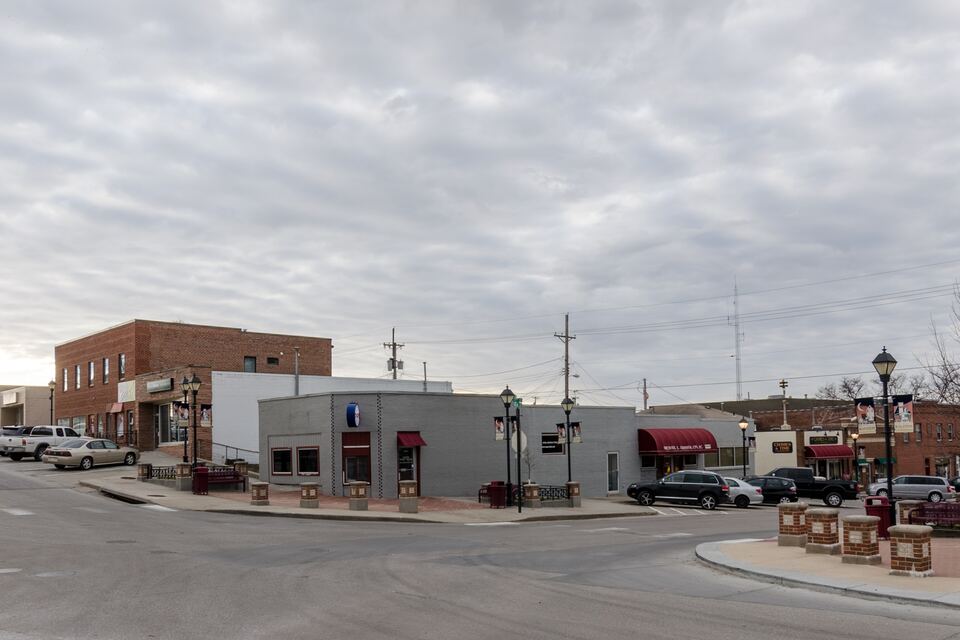 Downtown Ralston street corner with low brick commercial buildings and street lamps under an overcast sky.