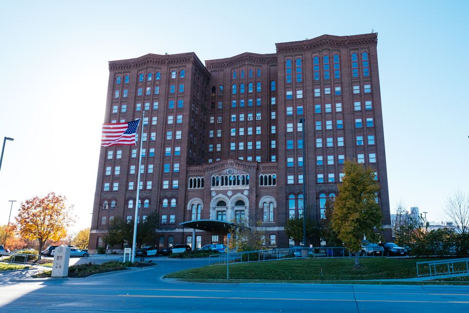 Large multi-story brick Livestock Exchange Building with an American flag in front and autumn trees.